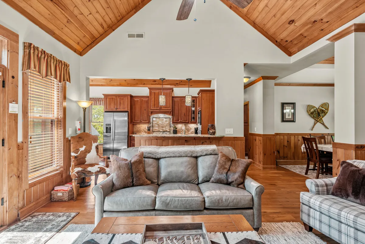 A seamless view of the main living area, dining space, and kitchen, featuring a plush sofa, a dining area, and a kitchen island. This open-concept shot showcases the connectivity between spaces, perfect for group gatherings and shared activities.