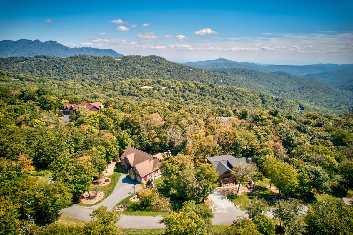 A panoramic view of a mountainous landscape with lush greenery and spacious surrounding properties, capturing the dramatic beauty of the Sugar Mountain region.