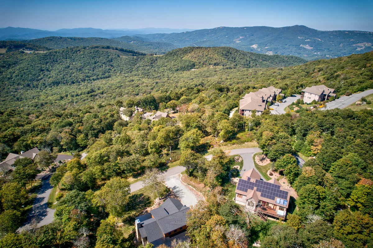 A sweeping view of the mountainous landscape, dotted with residential buildings and winding roads. The vista captures the allure of the region’s rolling hills and wooded areas, hinting at the scenic drives and exploration opportunities highlighted in the section. The tranquil mood evokes a sense of adventure and discovery.