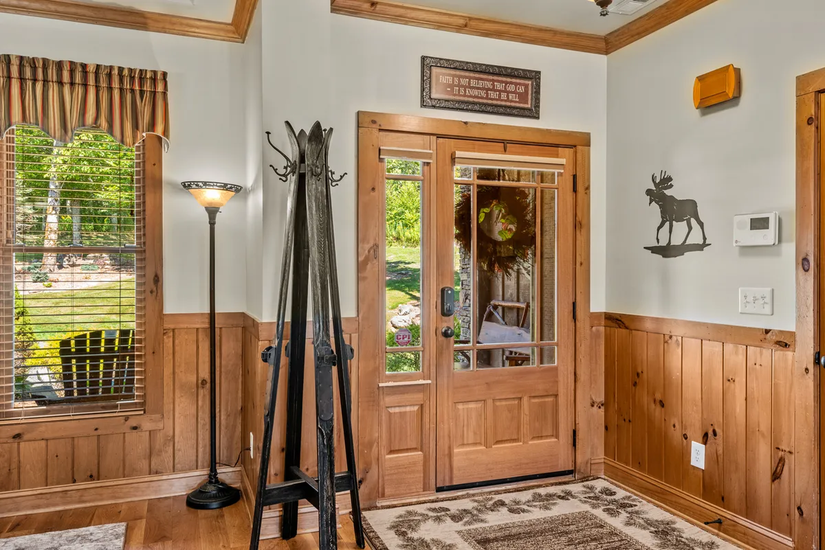 This image captures the welcoming entryway of The Trinity, featuring a wooden door, coat rack, lamp, and a window with a view. The natural light streaming in creates an inviting atmosphere, making it an ideal spot for greeting guests and setting the tone for group gatherings.